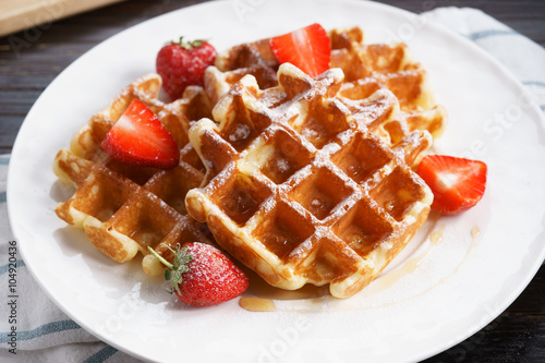 Homemade waffles with syrup and strawberry.