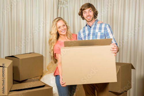Happy couple carrying a moving box