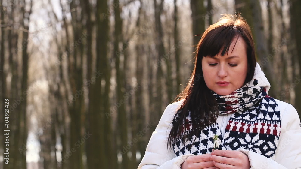 Sad girl sniffs and touches snowdrops in spring forest Sad girl sniffs and touches snowdrops in spring forest