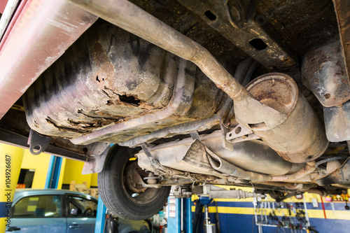 Car with rusty, damaged, corroded undercarriage at workshop for repair work  photo