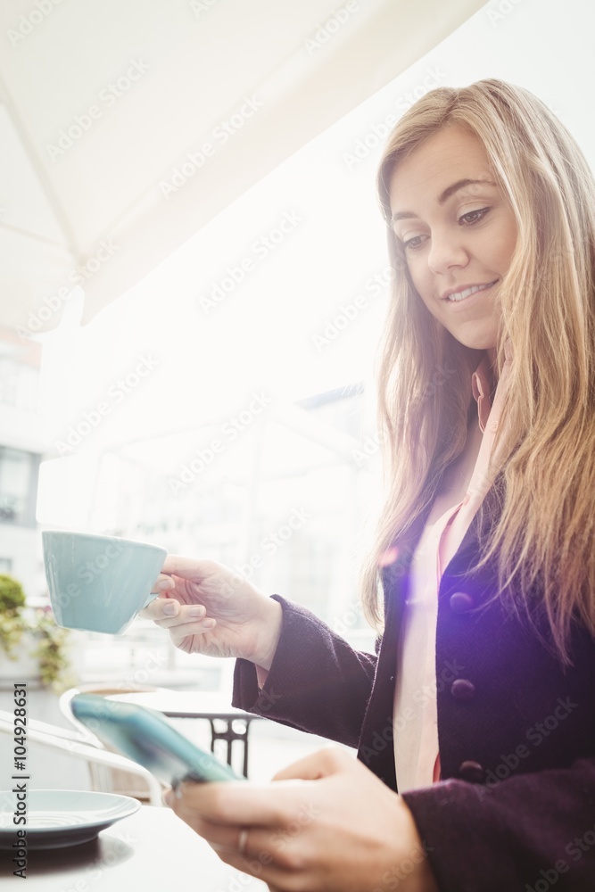 Woman using her smartphone and drinking coffee Woman using her smartphone and drinking coffee
