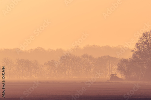 Misty morning with a tractor on a field