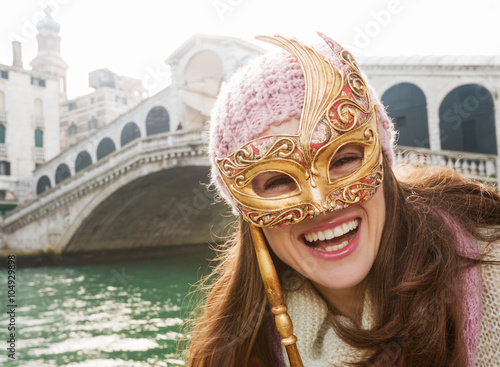 Happy woman holding Venice Mask in the front of Rialto Bridge