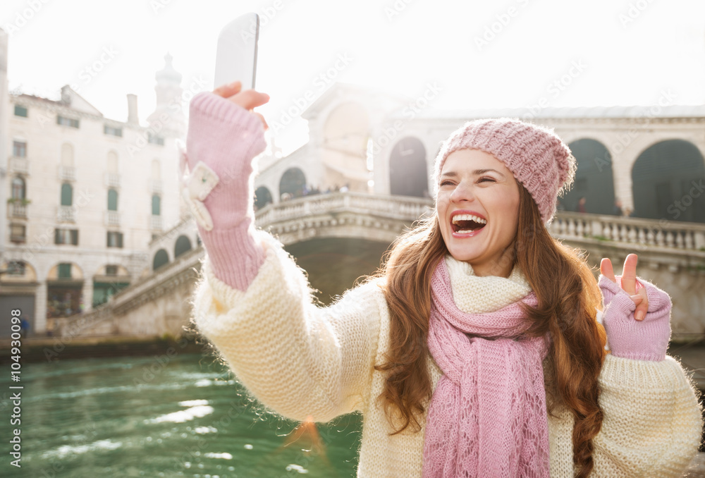 Fototapeta premium Woman tourist showing victory while taking selfie in Venice