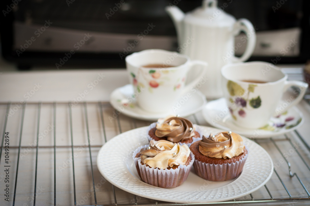 cream cheese and coffee cupcakes with tea pot on white wooden cream cheese and coffee cupcakes with tea pot on white wooden