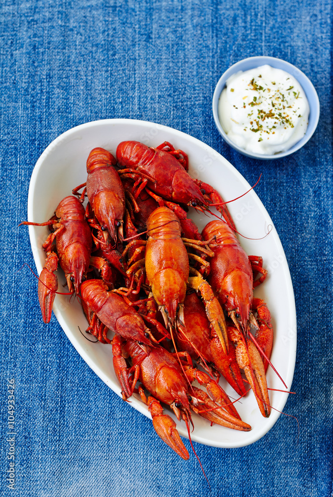 Boiled red crayfish on a white dish with sauce of grated horseradish in a gravy boat. top view Boiled red crayfish on a white dish with sauce of grated horseradish in a gravy boat. top view