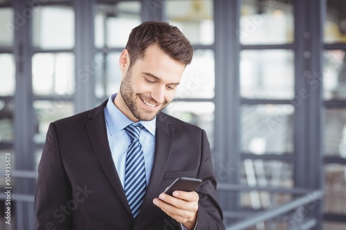 Businessman smiling while looking at mobile phone