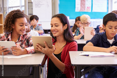 Teacher helping kids with computers in elementary school