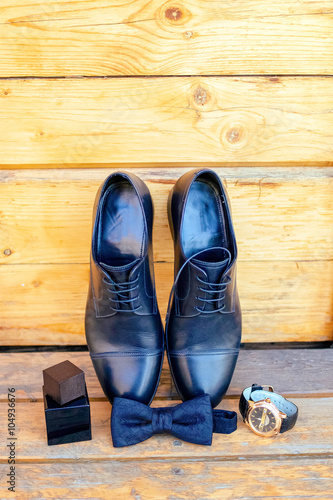 black men's shoes and bow tie on wooden floor