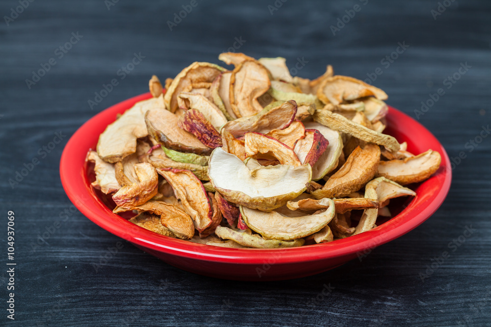 Red plate of dried apples on wooden background Red plate of dried apples on wooden background
