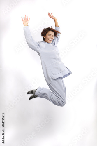 giovane donna in pigiama grigio , salta su sfondo bianco