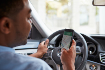 In car view of young male African American looking at maps app o