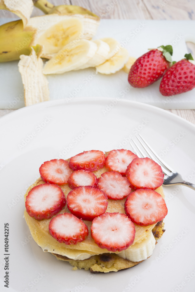 Stack of golden pancakes with strawberries, banana,