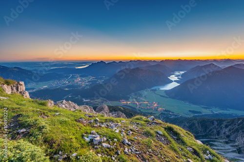 view from top of mountain to valley with lake plansee at sunrise photo