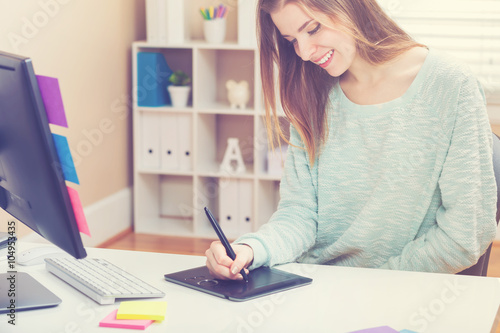 Happy young woman working with a pen stylus tablet
