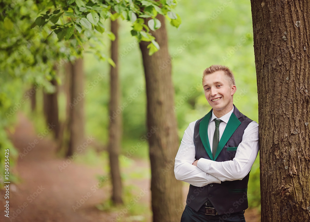 Handsome young groom posing outside in nature Handsome young groom posing outside in nature