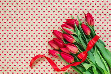 Bouquet of red tulips on hearts backgrounds. Copy space, holiday background