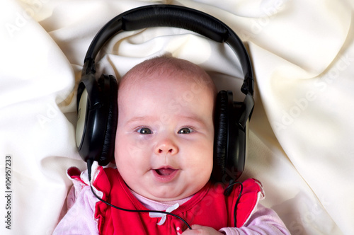 Adorable little girl lying in headphones