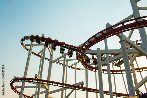 Theme Park Rollercoaster against blue sky .