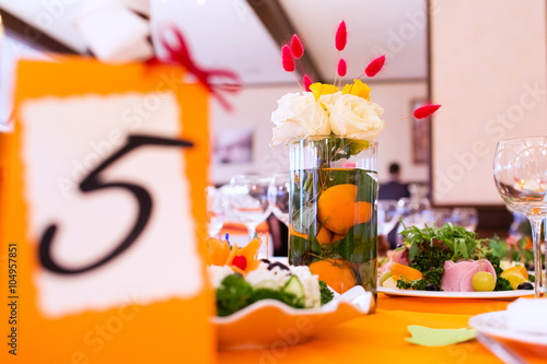 Wedding table decorated in orange colors with flower composition