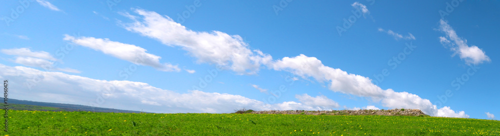 Panorama con delle bellissime nuvole nel cielo azzurro sopra una collinetta verde - Pianeta Terra Panorama con delle bellissime nuvole nel cielo azzurro sopra una collinetta verde - Pianeta Terra