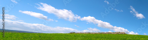 Panorama con delle bellissime nuvole nel cielo azzurro sopra una collinetta verde - Pianeta Terra