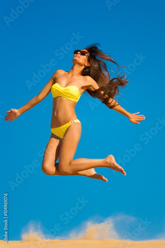 brunette woman yellow swimsuit jump