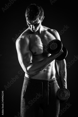 Man with naked torso and dumbbells on black background © nazarovsergey