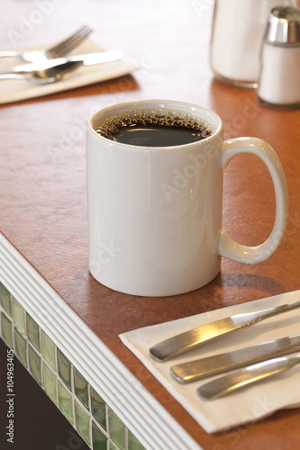 White ceramic mug with black coffee on counter in a typical American diner