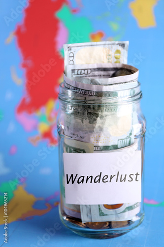 Savings for trip in glass bank on colourful map background