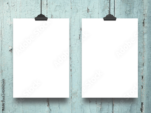 Close-up of two hanged paper sheets with clips on aqua wooden boards background