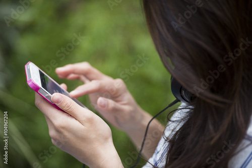 Young Asian woman is using a smartphone sitting on a bench