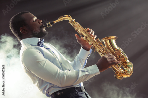 Wall Mural African American jazz musician playing the saxophone against smoky background
