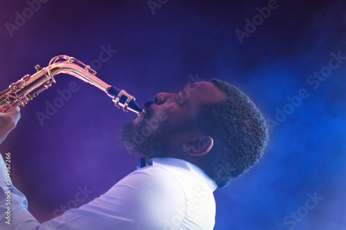 Sticker African American jazz musician playing the saxophone against colorful smoky back