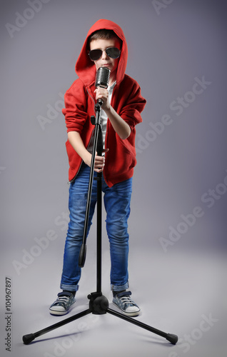 Little boy singing with microphone on a grey background