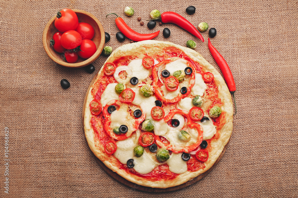 Delicious pizza with cheese and vegetables on sackcloth background
