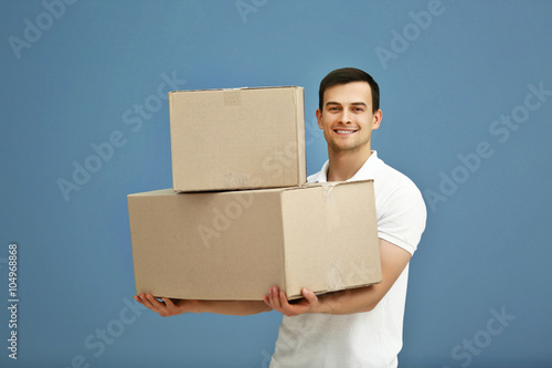 Man holding pile of carton boxes on blue background, close up