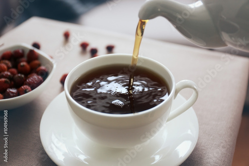 Pouring rose hip tea into cup, home atmosphere