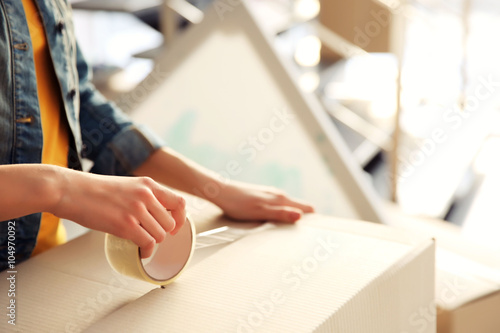 Foto Young girl sealing with tape big cardboard box for moving