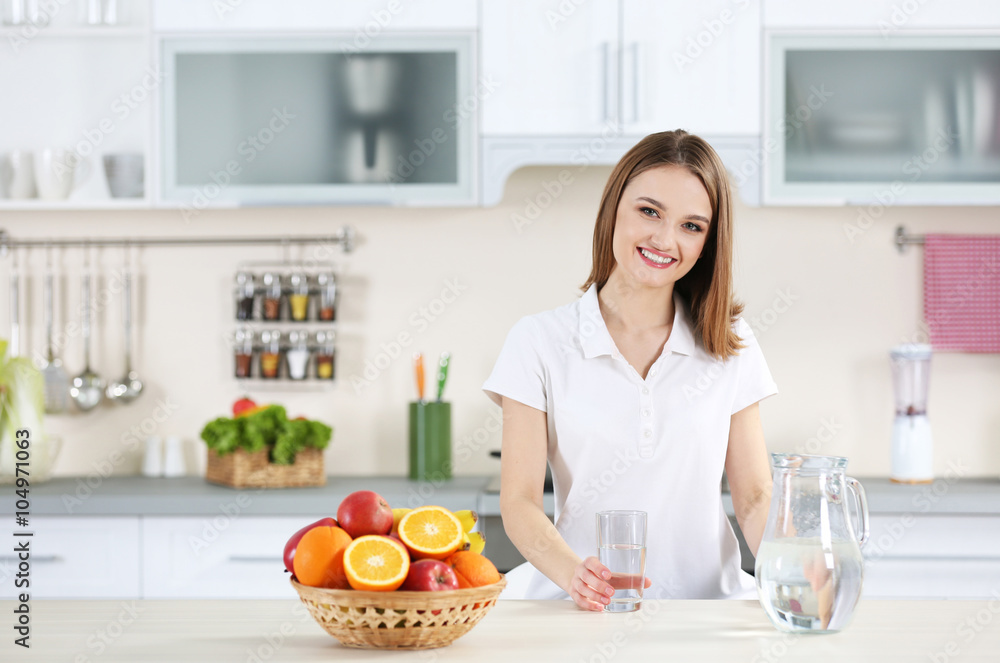 Young woman drinking water from glass in the kitchen