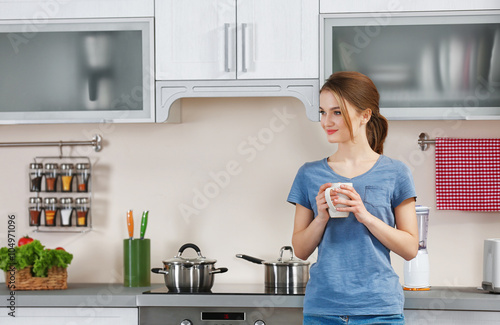 Young woman holding cup in the kitchen