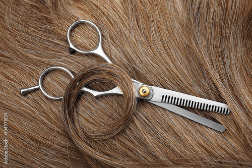 Hairdresser's scissors with brown hair, close up