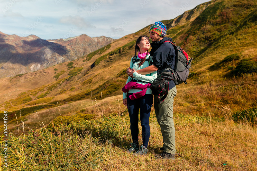 Traveler young loving couple on peak of mountain. Man kissing a woman with closed eyes.