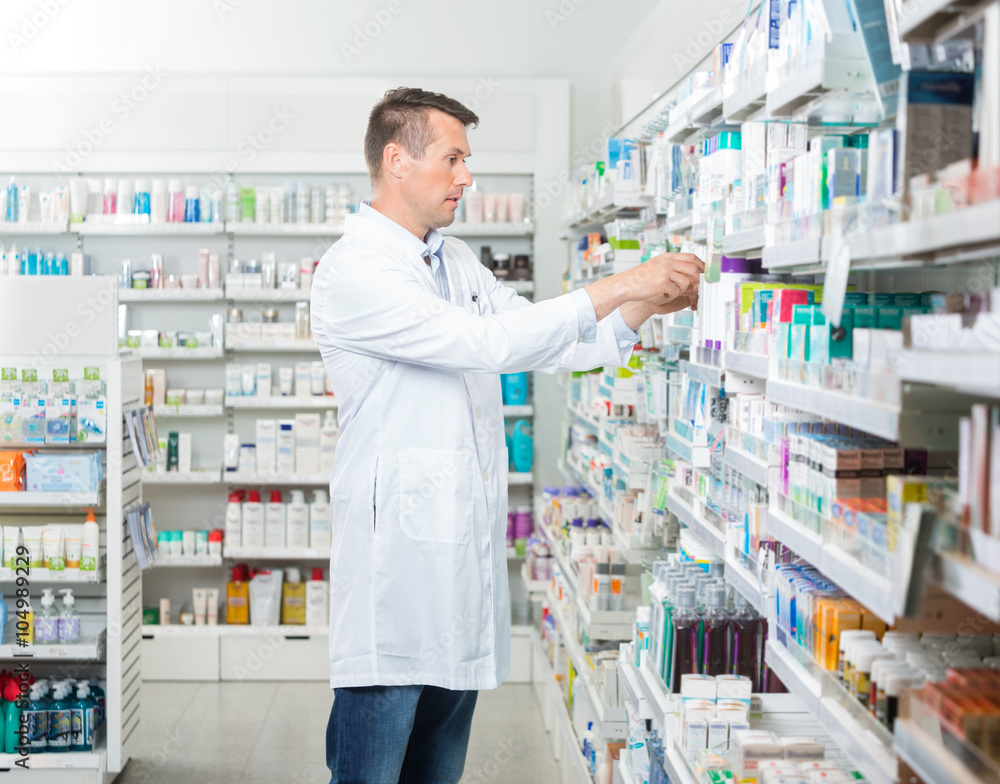 Female Chemist Arranging Products In Pharmacy