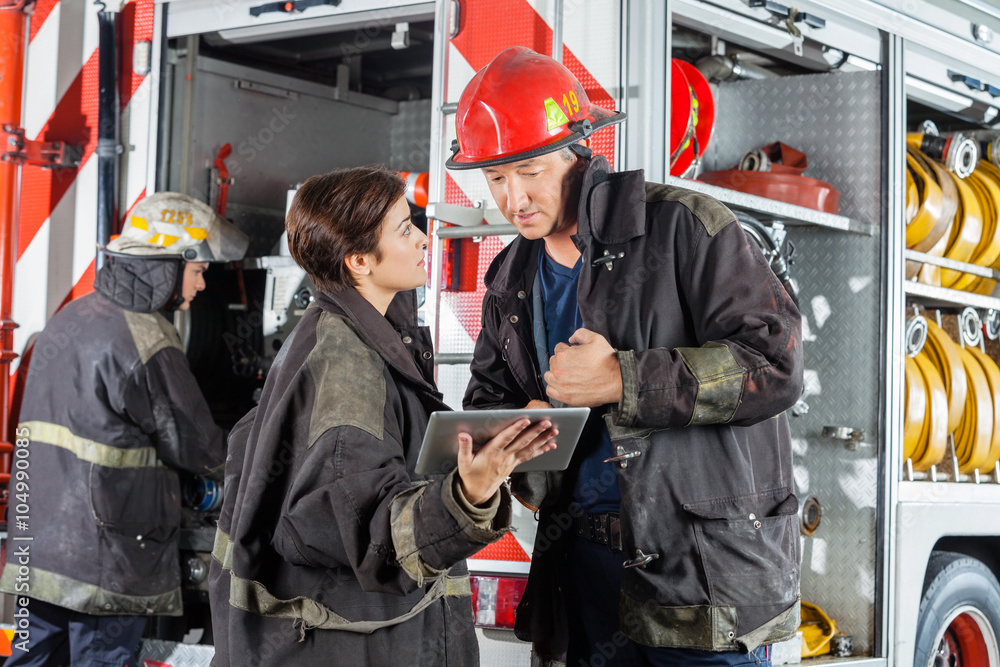 Obraz premium Firefighters Using Digital Tablet Against Truck