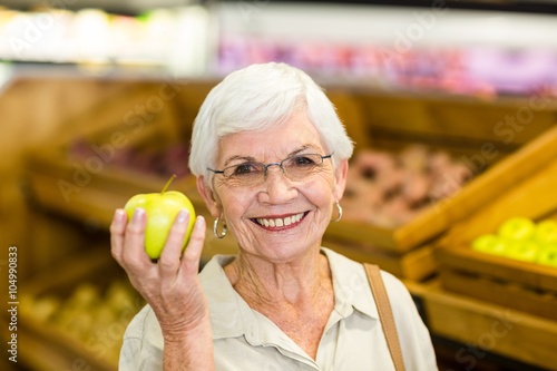 Senior woman holding and watching a green apple