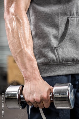 Muscular man with grey jumper holding dumbbell