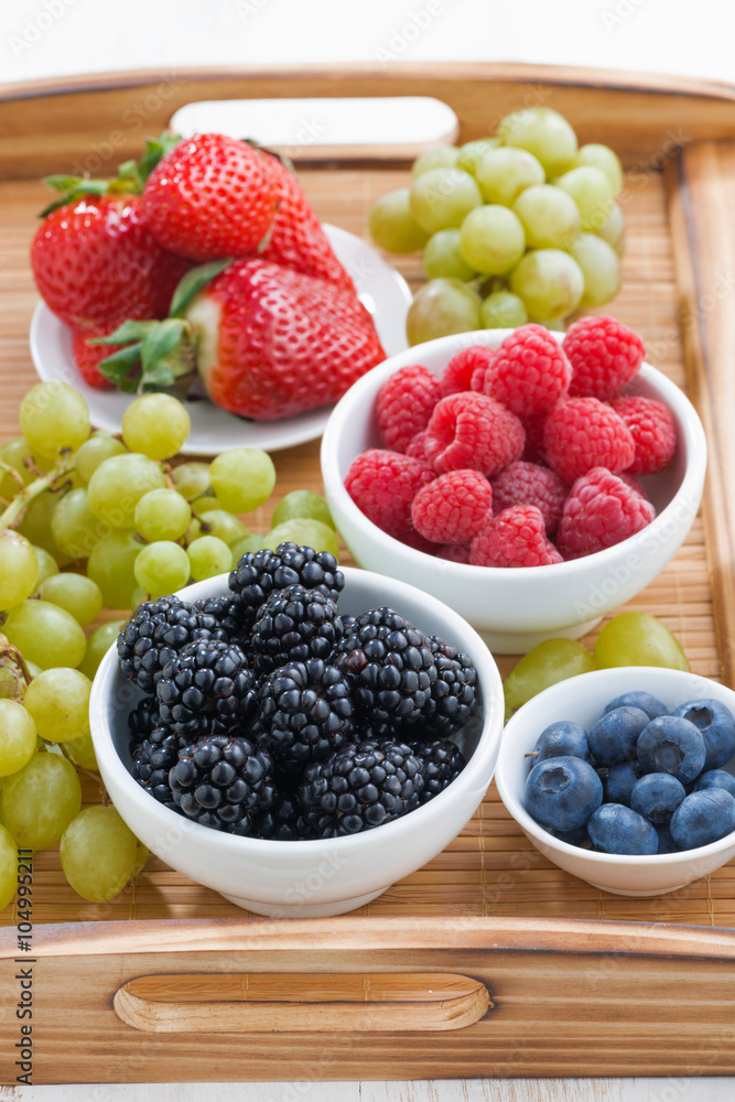 fresh berries in a bowl and green grapes on wooden tray fresh berries in a bowl and green grapes on wooden tray