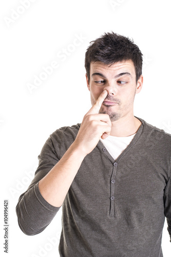 Young man with finger in his nose on a white background