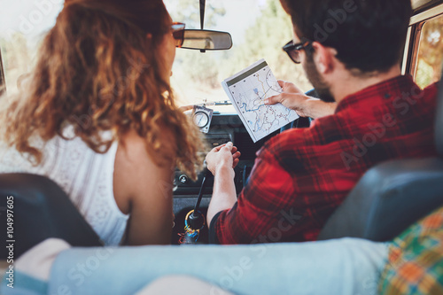 Young couple checking a map on roadtrip